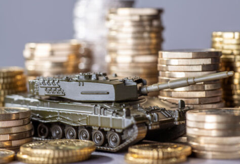 Tank between stacks of coins as a symbol of high armament expenditure